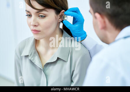 Portrait de belle jeune femme qui a son oreilles et l'ouïe à l'essai par un médecin en clinique, copy space Banque D'Images