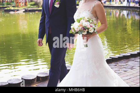 Mariage bouquet de fleurs de printemps frais. Bride holding bouquet de mariée blanche close up.Le groom holding par une main la mariée dans une robe de mariée blanche Banque D'Images