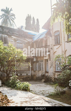 Complexe de bâtiments coloniaux délabrés sur une journée ensoleillée à Mumbai, Inde, entouré d'arbres Banque D'Images