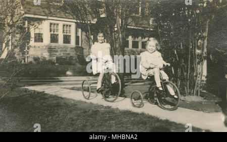 Meubles anciens c1923 photo, deux filles circonscription tricycles à la maison. Lieu inconnu, peut-être New York ou le New Jersey, USA. SOURCE : GÉLATINE D'ORIGINE. Banque D'Images