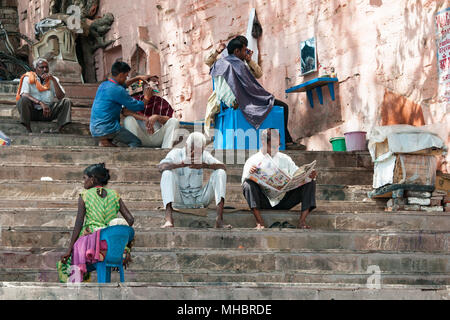 Varanasi, Inde - le 12 mars 2017 : les Indiens assis sur l'escalier et de lecture à la ville sainte de Varanasi en Inde. Banque D'Images