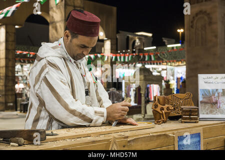 Dubaï, Émirats arabes unis - 4 décembre 2017 : artisan Sculpteur sur bois dans les vêtements nationaux dans le pavillon de la Turquie en Village mondial Banque D'Images