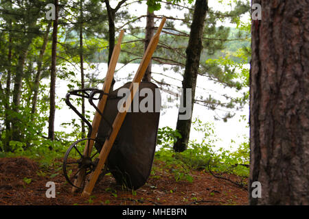 Brouette Vintage ld'poignées en bois ignification sur un arbre près d'un lac Banque D'Images