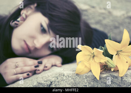 Triste jeune femme avec une pierre tombale fleurs couché sur Banque D'Images