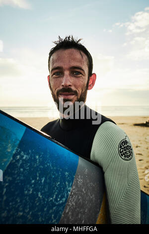 Un lieu de vie de plein air portrait d'un surfeur sur une plage juste après un surf. Banque D'Images