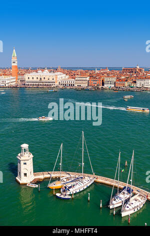 Voir des petits bateaux et phare sur grand canal que St Mark's Campanile sur arrière-plan sous ciel bleu à Venise, Italie (composition verticale). Banque D'Images