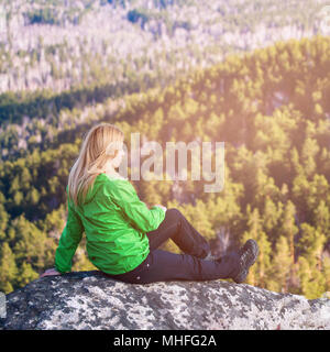 Jeune femme assise sur le bord de la falaise. Banque D'Images