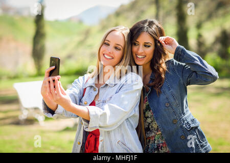 Deux jeunes femmes prenant une photographie selfies en parc urbain. Concept de vie. Banque D'Images