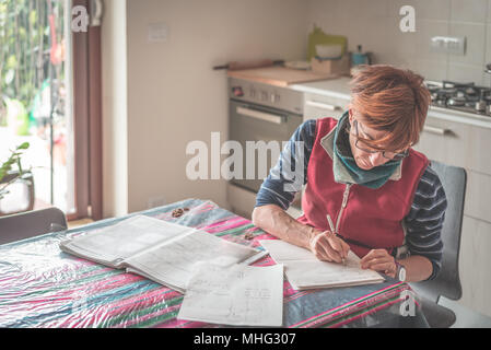 Femme à lunettes assis à table, la lecture et l'écriture les formalités administratives et de documents. Selective focus, home Interiors. Concept de travail à domicile. Banque D'Images