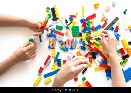 Les mains des enfants jouer avec des blocs lego colorés sur tableau blanc. Banque D'Images