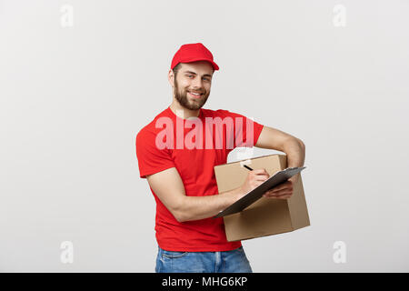 Portrait of smiling male delivery man writing on clipboard et holding box. Plus isolé sur fond blanc Banque D'Images