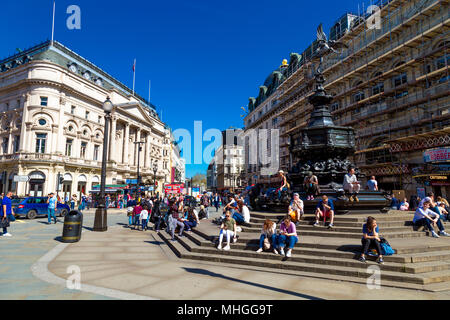 Occupé à Piccadilly Circus avec les touristes assis sur les marches de la fontaine Shaftesbury Memorial, London, UK Banque D'Images