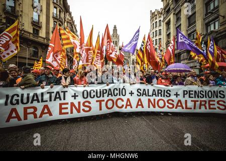 Barcelone, Espagne. 1 mai, 2018 : Des milliers de manifestants brandissant des drapeaux avec leur derrière leur bannière mars pendant une manifestation organisée par le maire les syndicats CC.OO et l'UGT, pour protester pour plus d'égalité, de l'occupation, des salaires et pensions sous le slogan "C'est maintenant notre tour' au 1er mai. Banque D'Images