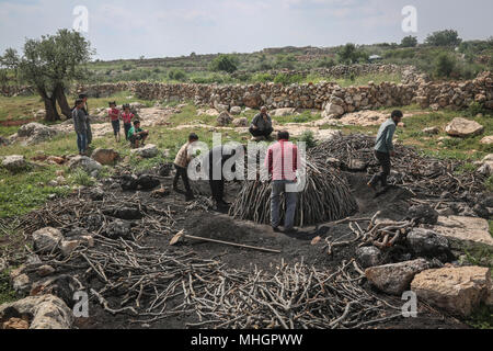 Le gouvernorat de Kafr Kila, Idlib, en Syrie. Apr 28, 2018. Syriens trier bois de chêne pour la fabrication du charbon dans le gouvernorat de Kafr Kila, Idlib, Syrie, 28 avril 2018. Les gens de Kafr Kila, une ville principalement habitée par les caractère ethnoreligieux groupe des druzes, a été la pratique de l'agriculture et de la fabrication du charbon pour des dizaines d'années. Credit : Anas ALkharboutli/dpa/Alamy Live News Banque D'Images