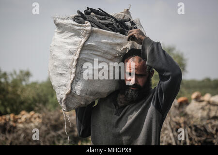 Le gouvernorat de Kafr Kila, Idlib, en Syrie. Apr 28, 2018. Une République homme porte un sac de charbon, fabriqué à partir de bois de chêne, dans le gouvernorat de Kafr Kila, Idlib, Syrie, 28 avril 2018. Les gens de Kafr Kila, une ville principalement habitée par les caractère ethnoreligieux groupe des druzes, a été la pratique de l'agriculture et de la fabrication du charbon pour des dizaines d'années. Credit : Anas ALkharboutli/dpa/Alamy Live News Banque D'Images