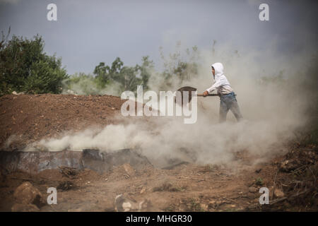 Le gouvernorat de Kafr Kila, Idlib, en Syrie. Apr 28, 2018. Un garçon syrien l'enterre dans une fosse en chêne pour faire du charbon dans la région de Kafr Kila, le gouvernorat d'Idlib, Syrie, 28 avril 2018. Les gens de Kafr Kila, une ville principalement habitée par les caractère ethnoreligieux groupe des druzes, a été la pratique de l'agriculture et de la fabrication du charbon pour des dizaines d'années. Credit : Anas ALkharboutli/dpa/Alamy Live News Banque D'Images