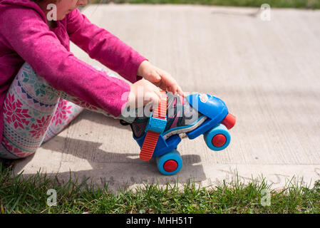 Bébé fille portant des genoux et coudes mise sur patins. Banque D'Images