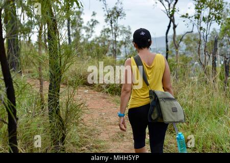 La Marche des femmes avec des vêtements de sport et une bouteille d'eau sur un chemin forestier, Mount Stuart des sentiers de randonnée, Townsville, Queensland, Australie Banque D'Images