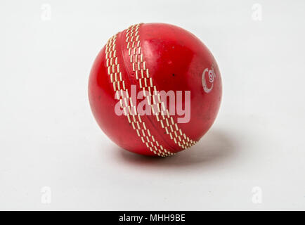 Gros plan sur une balle de Cricket rouge sur fond blanc. Banque D'Images