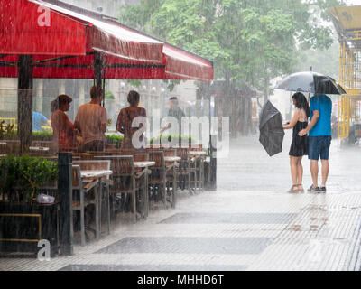 Les gens à l'abri de pluie et de couple avec parapluie au centre-ville de Buenos Aires, Argentine Banque D'Images