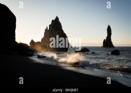 Vagues se briser contre les rochers au lever du soleil, à la plage de sable noir en Islande Banque D'Images