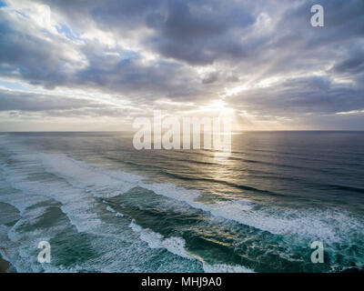 Coucher de soleil sur les vagues de l'océan en vertu de moody sky Banque D'Images