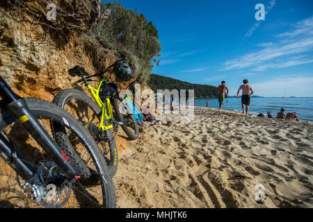 Deux hommes courir dans la mer après un vtt à Punta Ala, Toscane, Italie. Banque D'Images