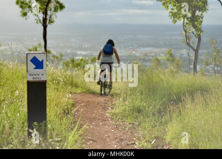 Vélo sur l'homme un chemin de gravier en fin d'après-midi avec vue sur Townsville, Mount Stuart des sentiers de randonnée, Townsville, Queensland, Australie Banque D'Images