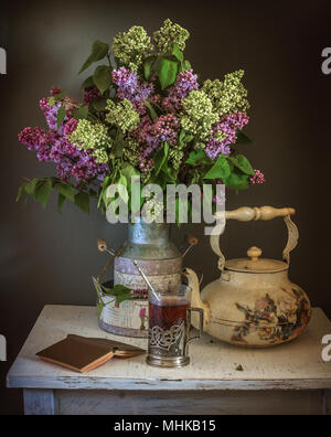 Nature morte avec fleurs et un verre de thé. vintage.silence. livre. électrique. Banque D'Images