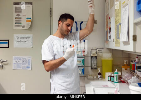 24 avril 2018, Allemagne, Berlin : l'infirmier l'Albanais Samed Qoshja prepates une infusion à la neurochirurgie de la Charité à la Benjamin Franklin Campus. Après des expériences positives, la plus grande clinique universitaire de la Charité à Berlin, s'efforce de répondre à son besoin de plus en plus d'infirmières de l'étranger. Photo : Kristin Bethge/dpa Banque D'Images