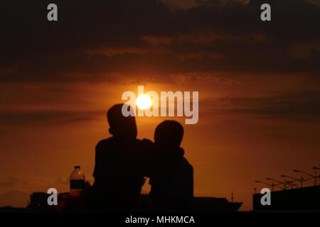 Manille, Philippines, Région de la capitale nationale. Apr 28, 2018. Les gens regardent le coucher du soleil comme il disparaît de la chaleur de la journée.C'est une chaude journée d'été et deux enfants regarder le coucher du soleil de l'horizon. Crédit : George Buid/ZUMA/Alamy Fil Live News Banque D'Images