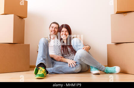 Photo de l'homme et la femme assis sur le plancher entre les boîtes de carton Banque D'Images