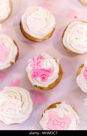 Cup cakes sont décorées avec des articles de bébé rose et blanc en l'honneur d'une petite fille sur le chemin. Banque D'Images