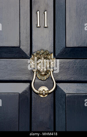 Close up de la vieille porte en bois noir avec un grand marteau en laiton en forme d'un lion et le numéro 11 sur la porte Banque D'Images