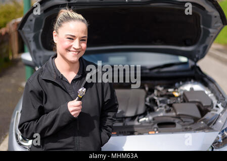 Une femme mechanic repairing a car le moteur au bord de la route Banque D'Images