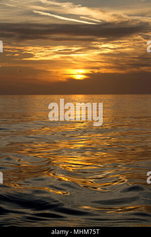 L'image colorée d'un brillant, Cloudscape sur une mer ondulante comme le soleil se couche sur la motion de notre Terre planst en rotation Banque D'Images