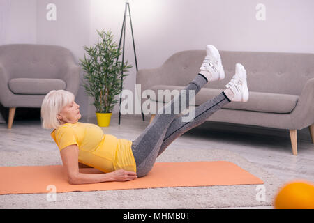 Senior woman doing agréable exercice de levage de jambe Banque D'Images
