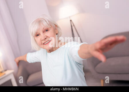 Happy elderly woman posing with arms spread and smiling Banque D'Images