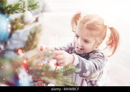 Joyeux Noël et de bonnes vacances jeune fille aider décorer l'arbre de Noël, la tenue des boules de Noël dans sa main Banque D'Images