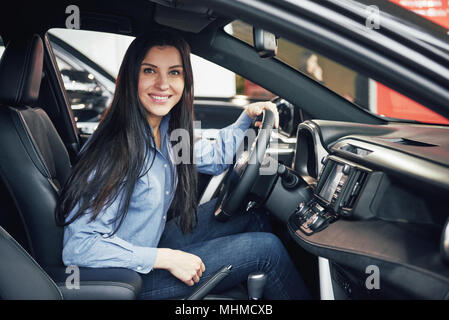 Vente, location d'auto, le consumérisme et le peuple concept - femme heureuse de prendre de clé de voiture concessionnaire en auto show ou salon Banque D'Images