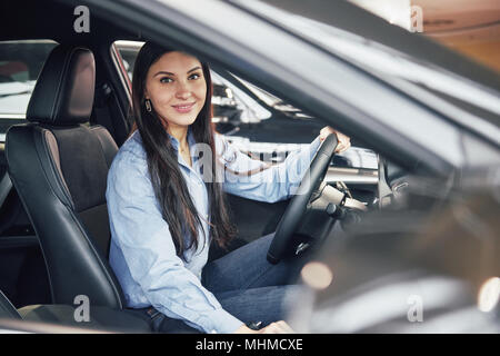 Vente, location d'auto, le consumérisme et le peuple concept - femme heureuse de prendre de clé de voiture concessionnaire en auto show ou salon Banque D'Images