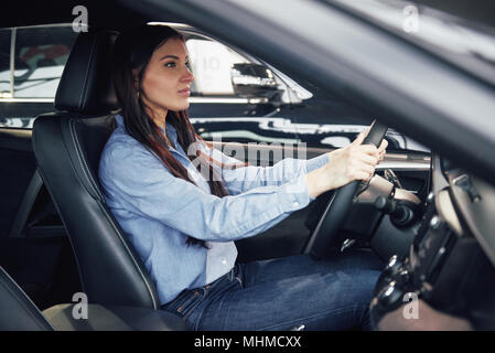 Vente, location d'auto, le consumérisme et le peuple concept - femme heureuse de prendre de clé de voiture concessionnaire en auto show ou salon Banque D'Images