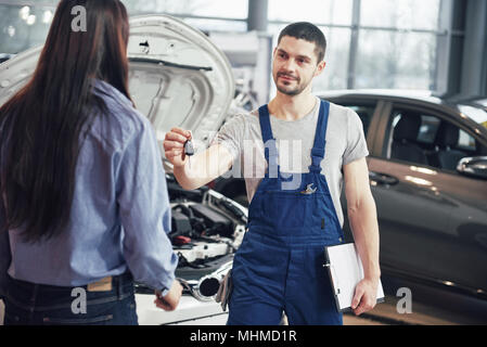 Portrait de mécanicien en donnant des clés de voiture à female client Banque D'Images