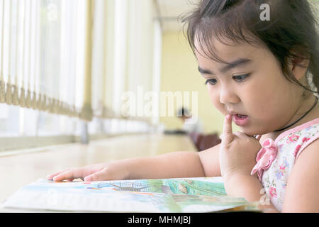 Les enfants sont des livres de lecture dans la bibliothèque.La lecture est le meilleur moyen d'apprendre. Améliorer la connaissance et l'imagination.Le grand livre jaune elle lit.A Banque D'Images