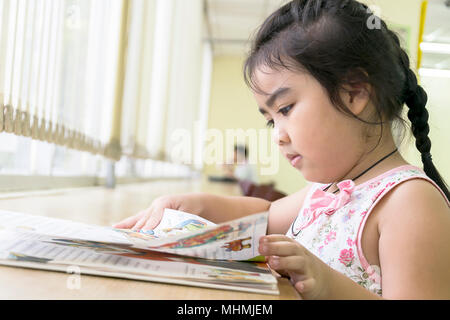 Les enfants sont des livres de lecture dans la bibliothèque.La lecture est le meilleur moyen d'apprendre. Améliorer la connaissance et l'imagination.Le grand livre jaune elle lit.A Banque D'Images