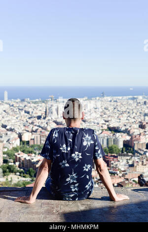 Libre d'un jeune homme de race blanche, vu de derrière, en haut d'une colline, l'observation de la ville de Barcelone, en Espagne, au-dessous de lui Banque D'Images