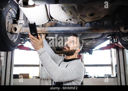 Homme mechanic repairing une voiture dans un garage. Banque D'Images