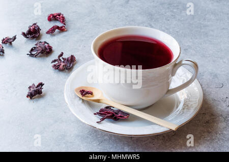 Red Hot Hibiscus tea cup en blanc avec des feuilles de thé d'hibiscus séchées. Boissons bio Banque D'Images