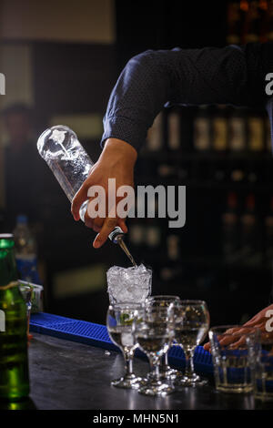 Barman verse le sirop dans le verre à cocktail dans un bar counter Banque D'Images