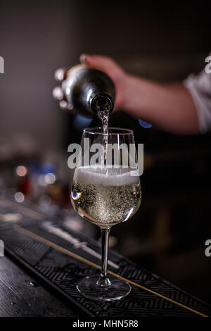 Barmann verse du Champagne en verre sur le comptoir du bar Banque D'Images